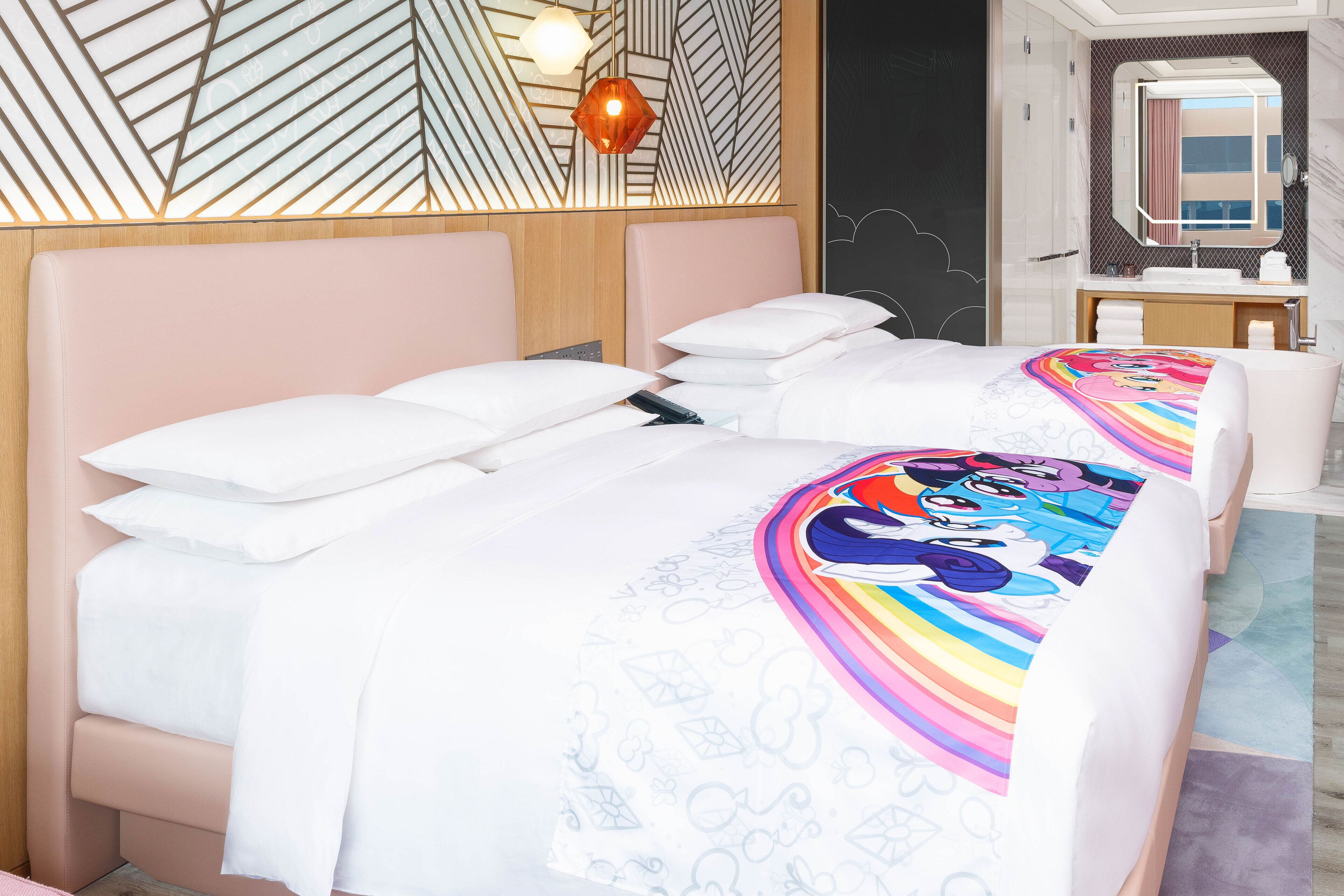 A hotel room with a bed, a bedside table, a mirror, and a bathroom with a sink and towel rack.