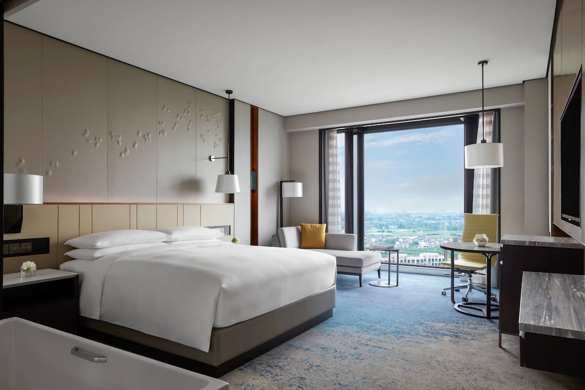 Une chambre d’hôtel moderne, dotée d’un grand lit, d’un bureau, d’une chaise et offrant une vue sur la ville.