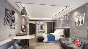 Een moderne hotelkamer met een bed, een bank, een eettafel en een televisie.