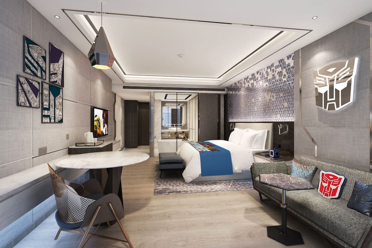 Une chambre d’hôtel moderne équipée d’un lit, d’un canapé, d’une table à manger et d’un téléviseur.