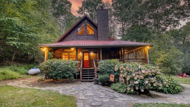 A cabin with a stone pathway leading to the entrance, surrounded by lush greenery and a forested backdrop. - Blue Ridge - Creek Front Paradise w/great outdoors (Blue Ridge)