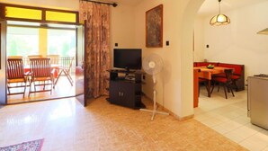A living room with a TV, a fan, and a dining area with a table and chairs. - Vacation home Akazie by Interhome (Balatonmariafurdo)