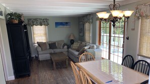 A cozy living room with a sofa, a wooden coffee table, and a dining table with chairs. - Beach House in Ocean Beach, Fire Island (Ocean Beach)