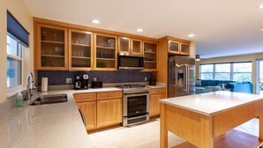 Una cucina moderna con mobili in legno, un frigorifero in acciaio inossidabile, un forno a microonde e un piano cottura a gas.