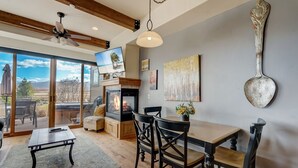 Una sala de estar acogedora con chimenea, comedor y un ventanal con vistas a una terraza.