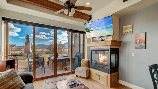 Una sala de estar con chimenea, un televisor grande y un ventanal corredera que da a una terraza.