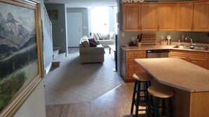A modern kitchen with wooden cabinets, a central island, and a dining area with stools. - Fernie Alpine Resort accommodation Thunder Ridge Chalet Truely Ski in/Ski out  (Fernie)