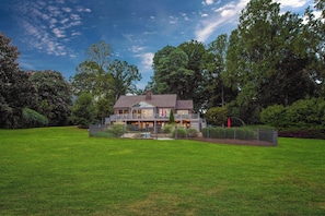 A large, two-story house with a spacious lawn and surrounding trees.