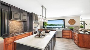 Una cocina moderna con armarios oscuros, una isla grande y vistas a un lago.
