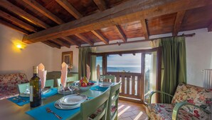 A dining area with a table set for four, a sofa, and a view of the sea.