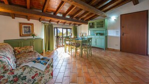 A room with a bed, a dining table with chairs, a green cabinet, and a wooden ceiling.