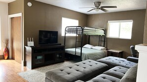 A bedroom with a bunk bed, a television, a desk, and a grey sofa. - Entire Home & Fenced Yard For Family & Pets (Independence)