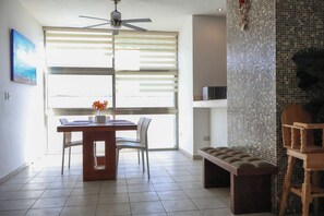 Un comedor con una mesa, sillas, un ventilador de techo, un banco y una pared decorativa.