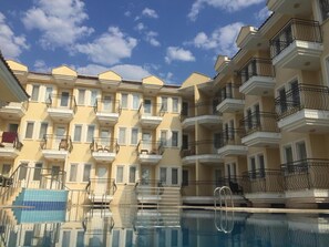A multi-story residential building with balconies, a swimming pool, and a clear sky. - Verdeport Hotel (Fethiye)