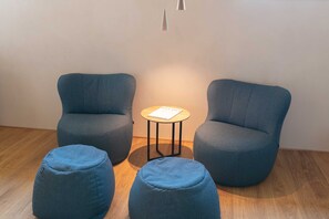 A room with two blue armchairs, a small round table with a book, and two ottomans. - Apartment 1 - Apartments Poldi (Sulzberg)