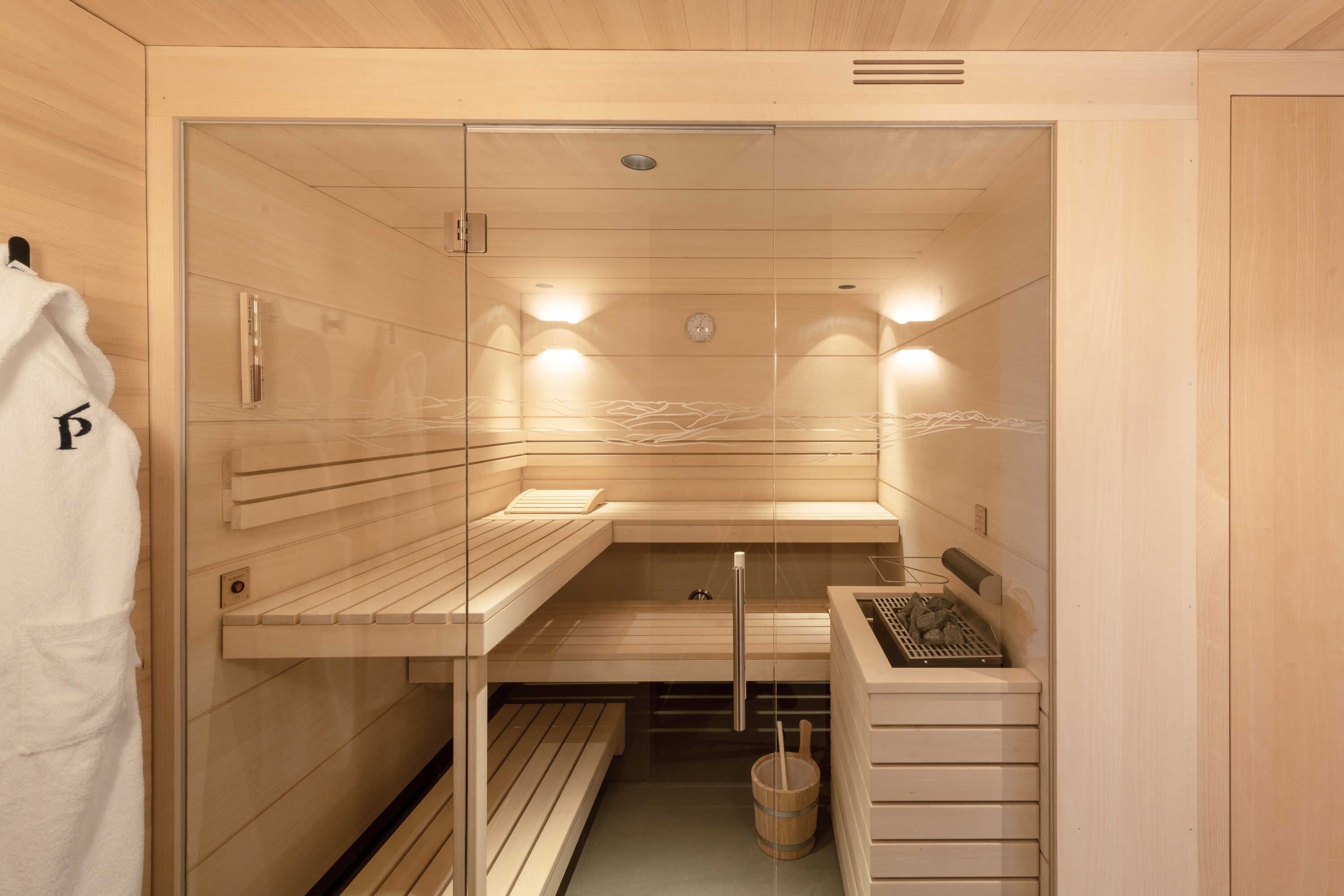 Eine Sauna mit Holzbänken, einem Handtuchhalter und einem Holzschrank.