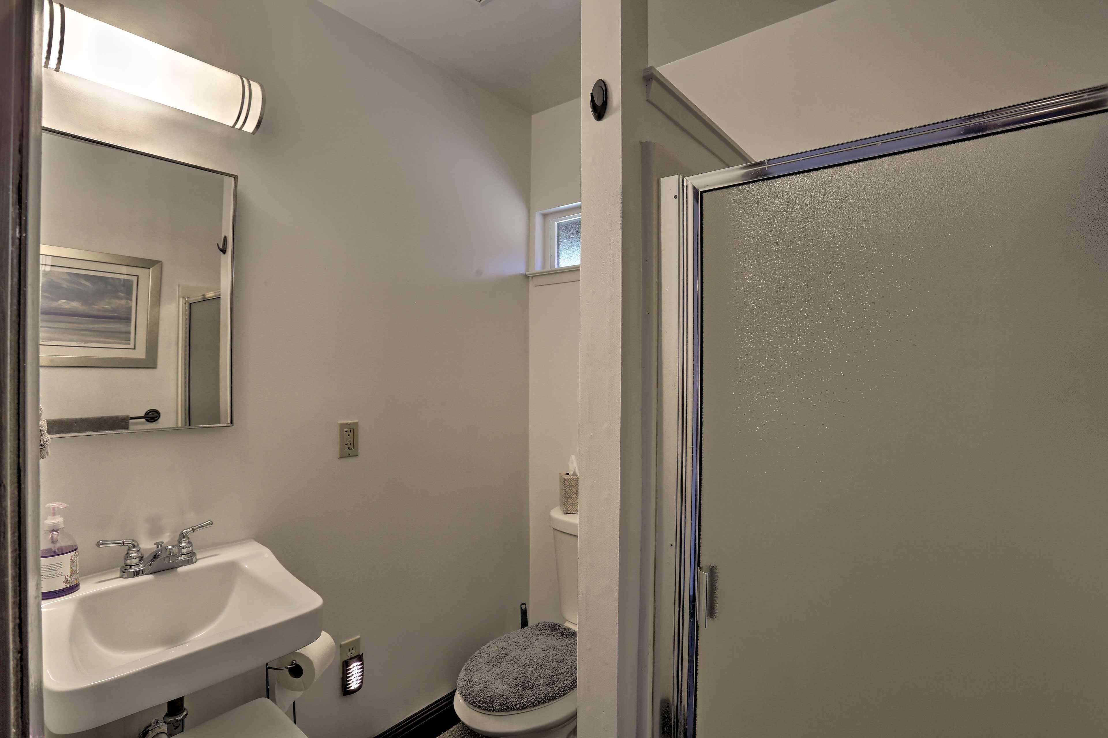 Un baño con lavamanos blanco, espejo, inodoro y puerta de ducha.
