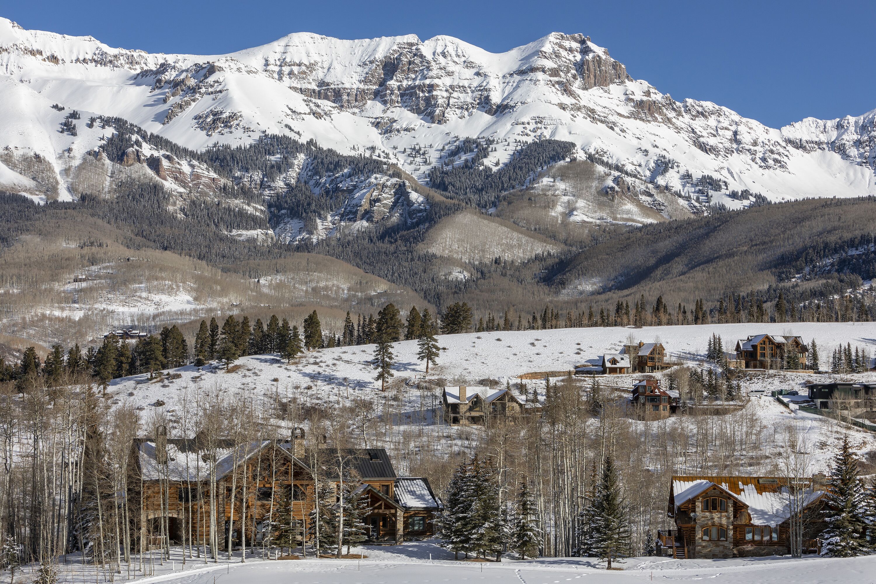 A snow-covered mountain range with a lodge in the foreground.
