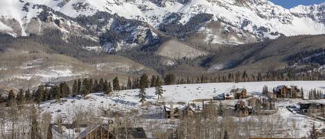 A snow-covered mountain range with a lodge in the foreground.