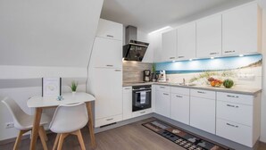 A modern kitchen with white cabinets, a built-in oven, and a countertop with a coffee maker and fruit.