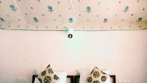 Una cama con ropa de cama estampada, un techo con diseño floral y una lámpara.