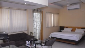 A bedroom with a bed, a desk, a chair, and a sofa.