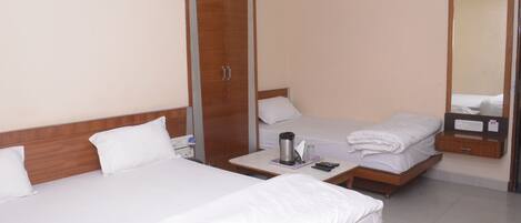 A hotel room with two single beds, a wardrobe, a bedside table with a coffee maker, and a mirror.