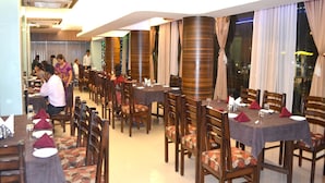 A restaurant with multiple tables and chairs, some with tablecloths and napkins.