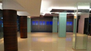 A modern lobby with polished floors, tall wooden columns, and glass elevator doors.
