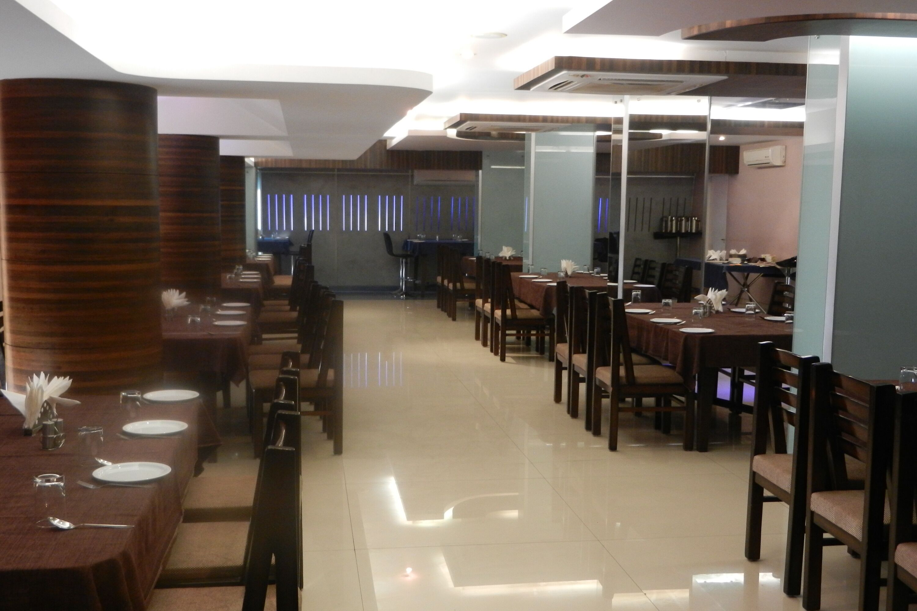 A restaurant with multiple dining tables and chairs, a polished floor, and a modern interior design.