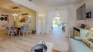 A spacious living area with a dining table, chairs, a sofa, and a TV. - Over the Moon - By Island Real Estate Vacations (Anna Maria)
