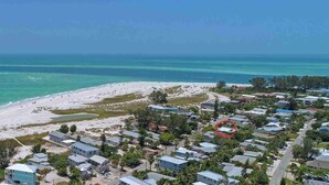 An aerial view of a coastal residential area with houses, a beach, and the ocean. - Over the Moon - By Island Real Estate Vacations (Anna Maria)