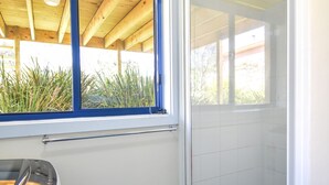 Un baño con ducha, ventana y lavabo.