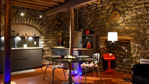Uma cozinha rústica com paredes de pedra, teto de madeira e um espaço de refeições com mesa e cadeiras.