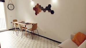 Un coin repas comprenant une table et des chaises, une horloge murale et un élément décoratif géométrique fixé au mur.