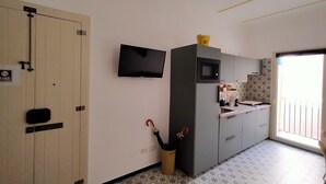 Une cuisine moderne équipée d’un téléviseur à écran plat, d’un four à micro-ondes et d’un évier. Une porte porte un panneau indiquant qu’il est interdit de se garer.
