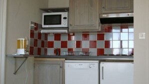 Een kleine keuken met een magnetron, een kleine koelkast en een koffiezetapparaat.
