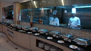 Un buffet avec différents plats présentés dans des récipients et un chef en uniforme.