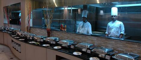 A buffet setup with various food containers and a chef in uniform.