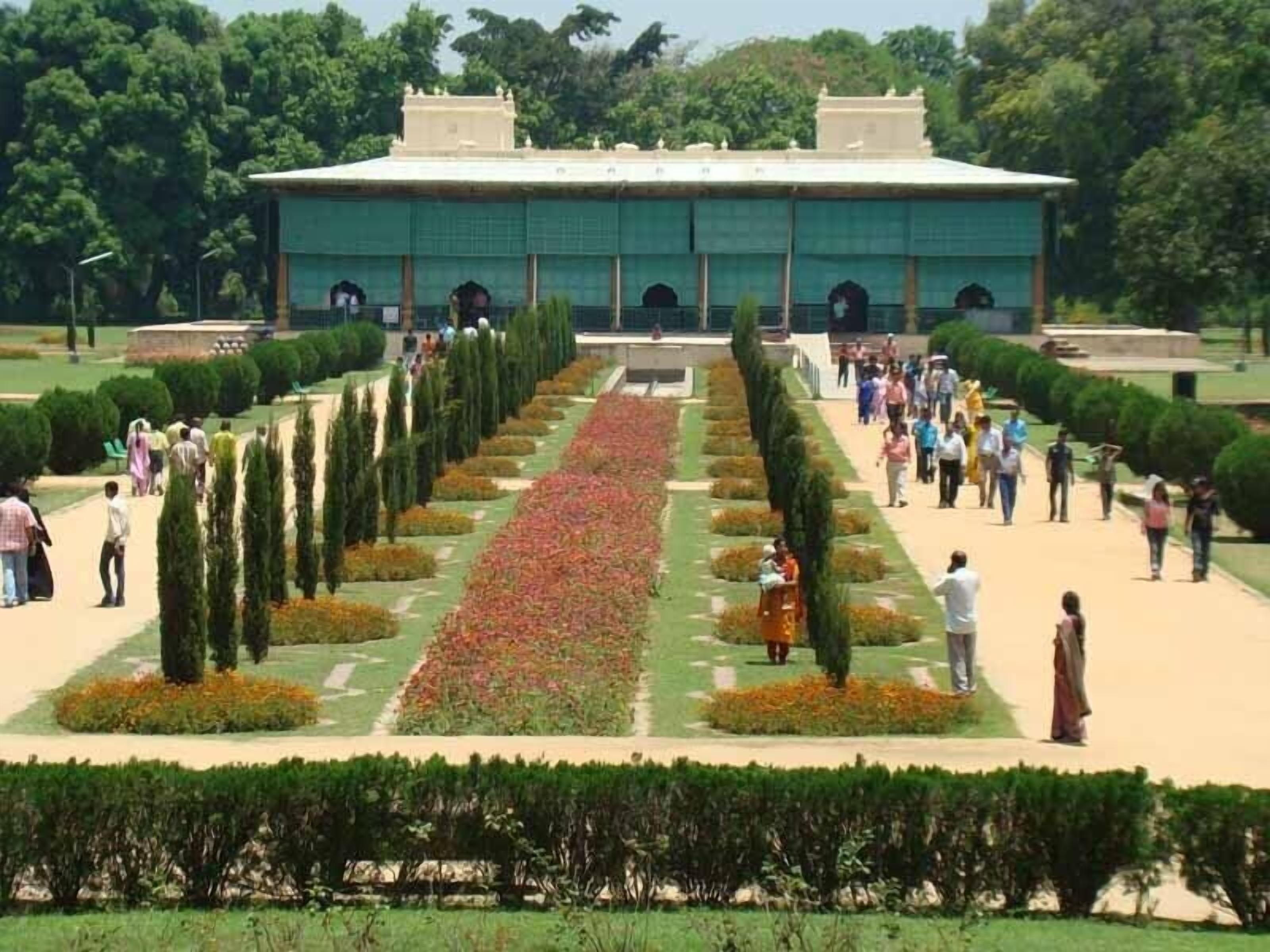 Un edificio grande con un patio central rodeado de setos cuidados y macizos de flores.