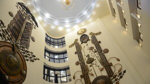 Un atrium à plusieurs niveaux, agrémenté d’œuvres d’art en métal décoratif sur les murs, d’un grand escalier et d’un lustre moderne.