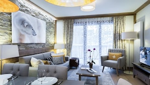 A modern living room with a stone wall, a large painting, a sofa, a coffee table, and a television. - New apartment Courchevel center 6 pers., parking, ski-in access (Courchevel 1550)