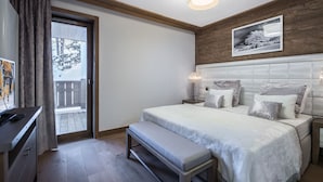 A bedroom with a large bed, a bench, a desk, and a window with curtains. - New apartment Courchevel center 6 pers., parking, ski-in access (Courchevel 1550)
