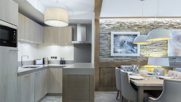 A modern kitchen with a central island, stainless steel appliances, and a dining area with a stone accent wall and artwork. - New apartment Courchevel center 6 pers., parking, ski-in access (Courchevel 1550)