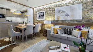 A modern living room with a stone accent wall, a large polar bear artwork, and a dining area with a wooden table and chairs. - New apartment Courchevel center 6 pers., parking, ski-in access (Courchevel 1550)