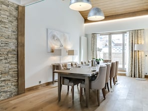 Un comedor moderno con una pared de acento de piedra, un cuadro grande y vistas de la ciudad a través de amplias ventanas.