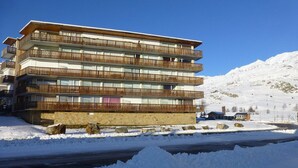Een hotel met meerdere verdiepingen en balkons, met een besneeuwde berg op de achtergrond.