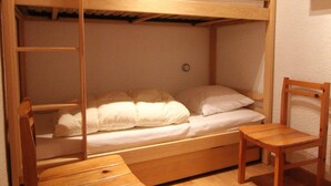 Een stapelbed met houten frame, een enkel bed beneden en een houten stoel.