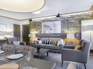 Un salon moderne avec un mur en pierre, des canapés gris et un grand tableau abstrait.