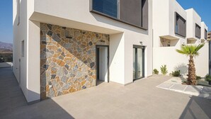 A modern house with a stone facade, a glass door, and a small palm tree in the yard. - Villa Barzinu (Isla de Fraile) (Aguilas)